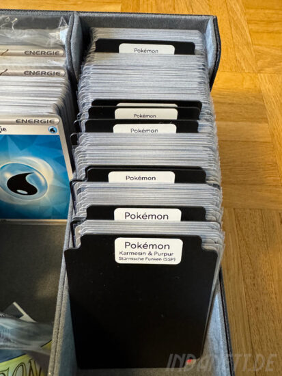 Viele Pokékom-Karten in einer Box, getrennt durch beschriftete Trenner aus Plastik.